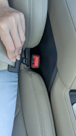 Hand is securing seatbelt in a contemporary vehicle, highlighting the plush leather seats and safety...