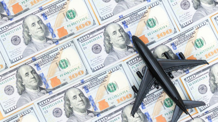 An airplane model rests atop a backdrop of US hundred dollar bills, symbolizing travel expenses, financial planning for trips, and the concept of saving money for future adventures. Investment.の写真素材