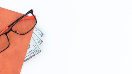 A financial planning concept featuring a book, glasses, and money, isolated on a white background. Ideal for illustrating business, finance, education, or personal finance themes. Perfect for mockups.の写真素材