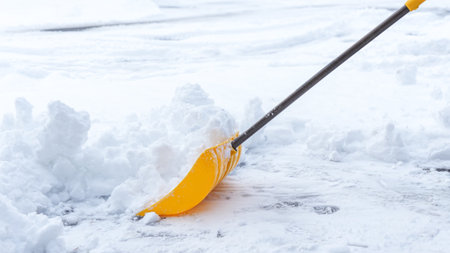 Man shoveling snow off of his driveway after a winter storm in Canada. Man with snow shovel cleans sidewalks in winter. Winter timeの写真素材