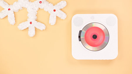 A sleek white CD player with a red disc sits on a beige background, paired with a white festive decoration. Ideal for music lovers and seasonal projects, this isolated object adds a touch of elegance.の写真素材