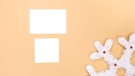 Flat lay mockup with a white snowflake ornament and blank cards on a peach background. Great for...