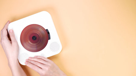 Discover the charm of a vintage CD player on a beige background. Hands delicately operate the...