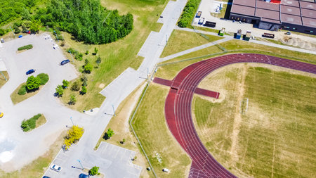 Aerial perspective of a colorful athletic track with adjacent green areas and parking lots, highlighting an active sports facility atmosphereの写真素材