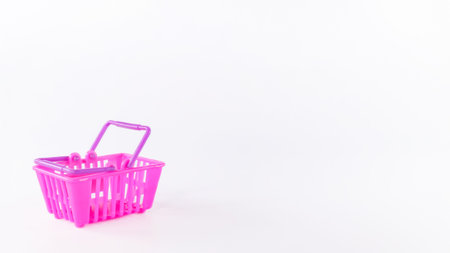Bright pink shopping basket placed on a minimalistic white background, perfect for showcasing retail...
