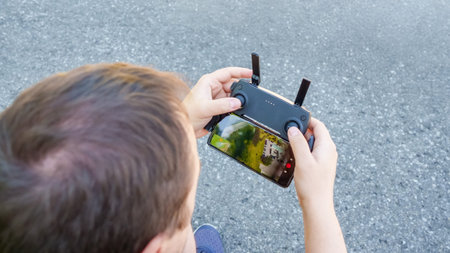 Individual is controlling a drone with a smartphone, capturing aerial imagery of the landscape,...