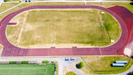 Aerial perspective of a running track featuring red lanes and grassy areas, highlighting an open...