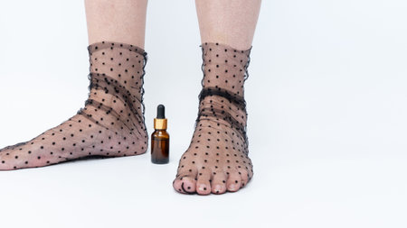 Tired legs and feet in sheer polka dot stockings next to an amber bottle, emphasizing the need for...