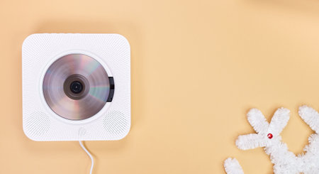 A compact CD player is shown against a tan background, accompanied by a white stuffed animal. Perfect for children s room decor, music enjoyment, or creative text placement.の写真素材
