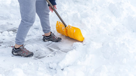 Man shoveling snow off of his driveway after a winter storm in Canada. Man with snow shovel cleans sidewalks in winter. Winter timeの写真素材