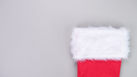 Red Christmas stocking featuring a plush white trim set against a smooth gray background, ideal for...