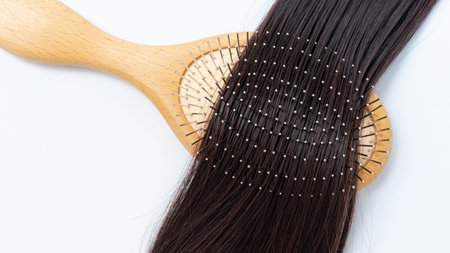 Wooden hairbrush rests on shiny, healthy hair, highlighting beauty and care in a clean, minimalist...