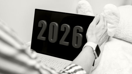 A person with light skin holds a laptop with digital display showing the year 2026.の写真素材