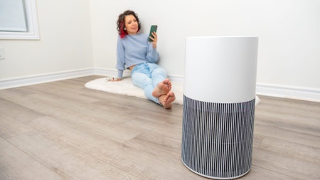 Woman is comfortably seated at home, enjoying fresh air and using her smartphone, with a stylish air...