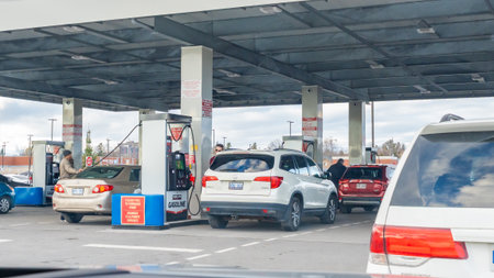 Ottawa ON, Canada - November 22, 2025: Vehicles are seen refueling at a Costco gas station with multiple pumps and a covered area, cloudy sky aboveのeditorial素材