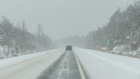Gatineau QC, Canada - November 30, 2025: Vehicle navigating a snow-covered highway during a...