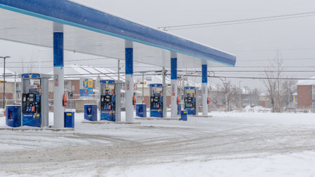 Gatineau QC, Canada - November 30, 2025: Gas station featuring multiple fuel pumps surrounded by snow, winter conditions impacting visibility and accessのeditorial素材