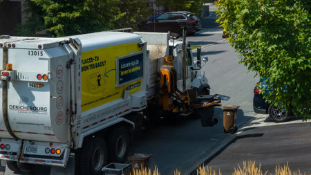 Gatineau QC, Canada - September 10, 2025: Garbage truck is actively collecting trash from curbside bins in a residential neighborhood, highlighting community cleanliness effortsのeditorial素材