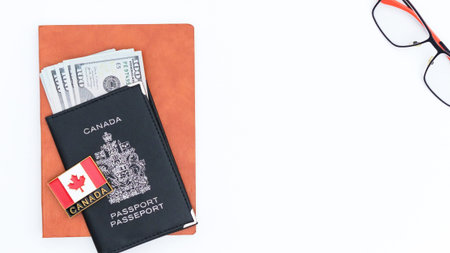 Ottawa, ON Canada - July 13, 2025: A flat lay of a Canadian passport, cash, glasses, and a notebook...