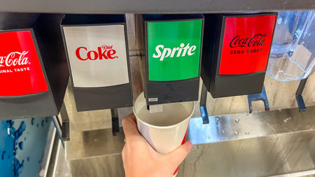 St Augustine FL, USA - March 07, 2026: A hand is positioned under a soda fountain dispenser, filling...
