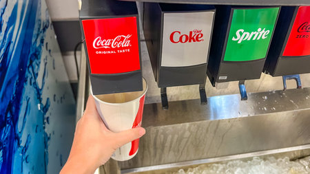St Augustine FL, USA - March 07, 2026: Hand holding a cup beneath a Coca-Cola dispenser in a...