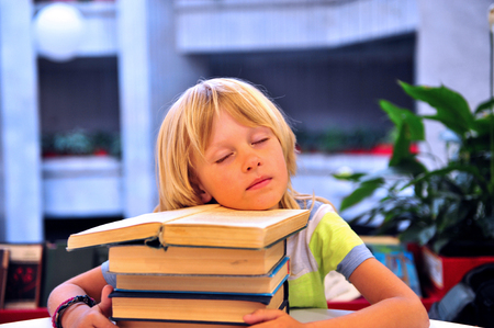 Happy cute boy sleeping with booksの写真素材