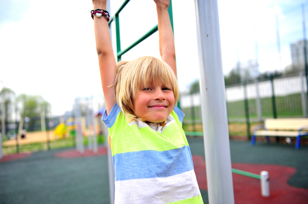 Adorable little boy hanging on kids playground, summer sceneの写真素材