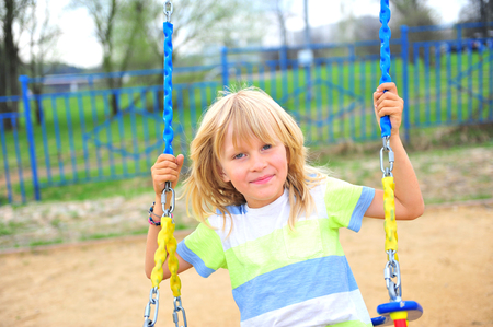 Happy boy on swing at the playgroundの写真素材