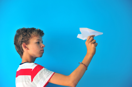 Boy with a paper airplane on blue backgroundの写真素材