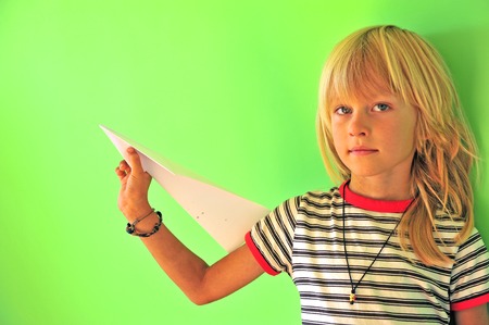 Little boy with paper airplane at green wall backgroundの写真素材