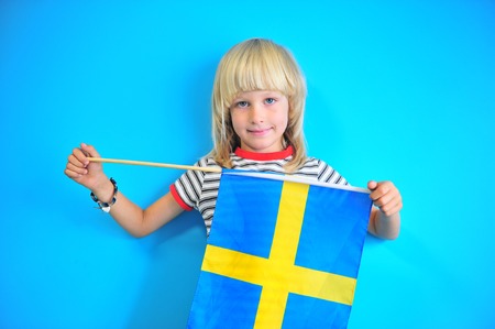 Cute blonde hair kid holding a flag of Swedenの写真素材