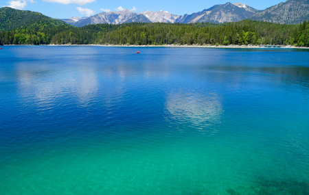Aerial view of beautiful alpine lake with clear turquoise water and mountains in background.