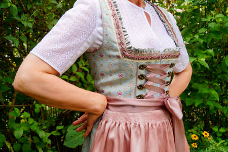 A woman in a dirndl is standing in a garden.の写真素材