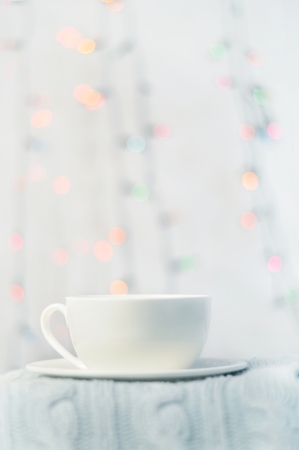 white cup and saucer stands on a knitted cushion on a blue backgroundの写真素材