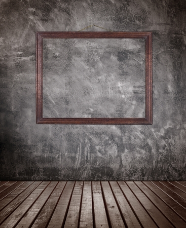 Old wooden floor room with picture frame hanging on the  ragged concrete wall の写真素材