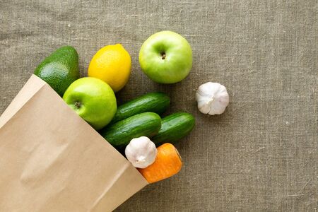 Grocery paper bag with vegetables and fruits on textile backgroundの写真素材
