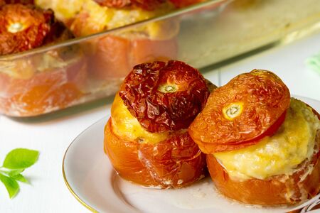 Baked tomatoes stuffed with minced chicken and cheese on a white plate.の写真素材