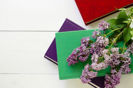 Hardback books with branch of lilac on a white background.の写真素材