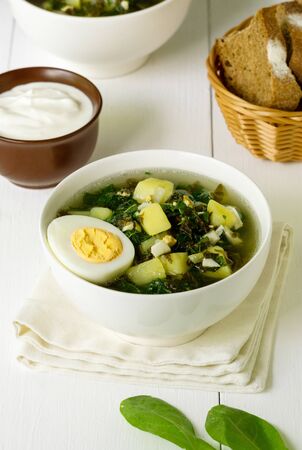 Green vegetable soup with sorrel leaves and eggs in a white bowl.の写真素材
