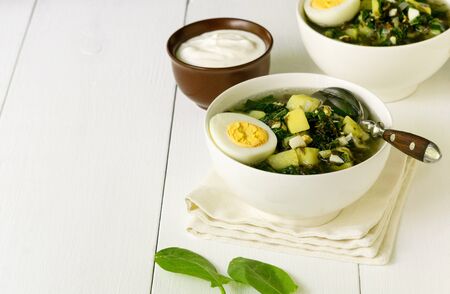 Green vegetable soup with sorrel leaves and eggs in a white bowl.の写真素材