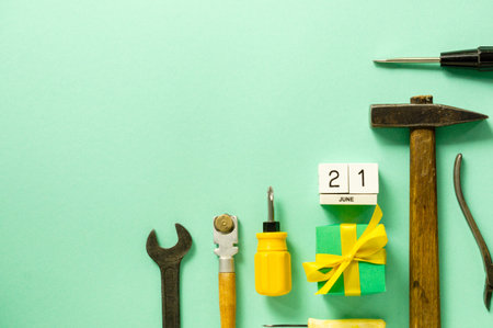 Flat lay for father's day with tools and gift box on a mint background.