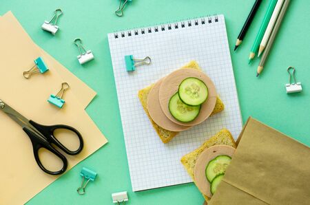 School flat lay with stationery and sausage sandwiches on a mint background.の写真素材