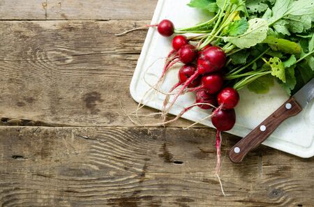 Bunch of garden radish on old wooden background. Space for text.の写真素材