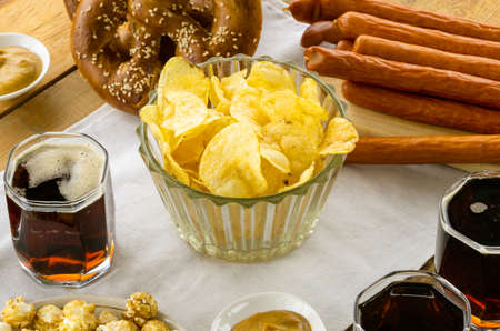 Glass bowl of potato crisps with beer on a wooden table.の写真素材
