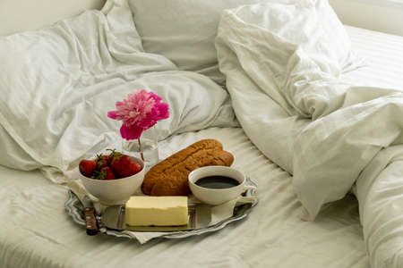 Breakfast in bed. Tray with black coffee, baguette and strawberries.の写真素材