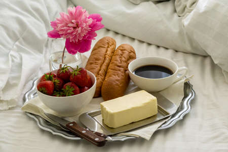Breakfast in bed. Tray with black coffee, baguette and strawberries.の写真素材