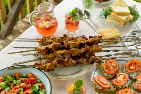 Dinner table with barbecue, snacks and strawberry lemonade outdoorsの写真素材