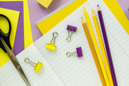 Back to school flat lay. Yellow and lilac stationery on a color background.