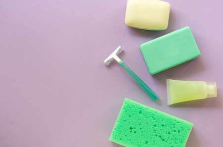 Flat lay of bath and hygiene products. Razor, soap bar and washcloth on a lilac background. Space for textの写真素材