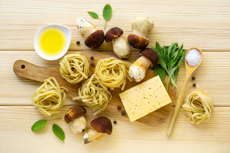 Ingredients for cooking pasta. Fettuccine with porcini mushrooms, cheese and sage leaves on a light wooden backgroundの写真素材